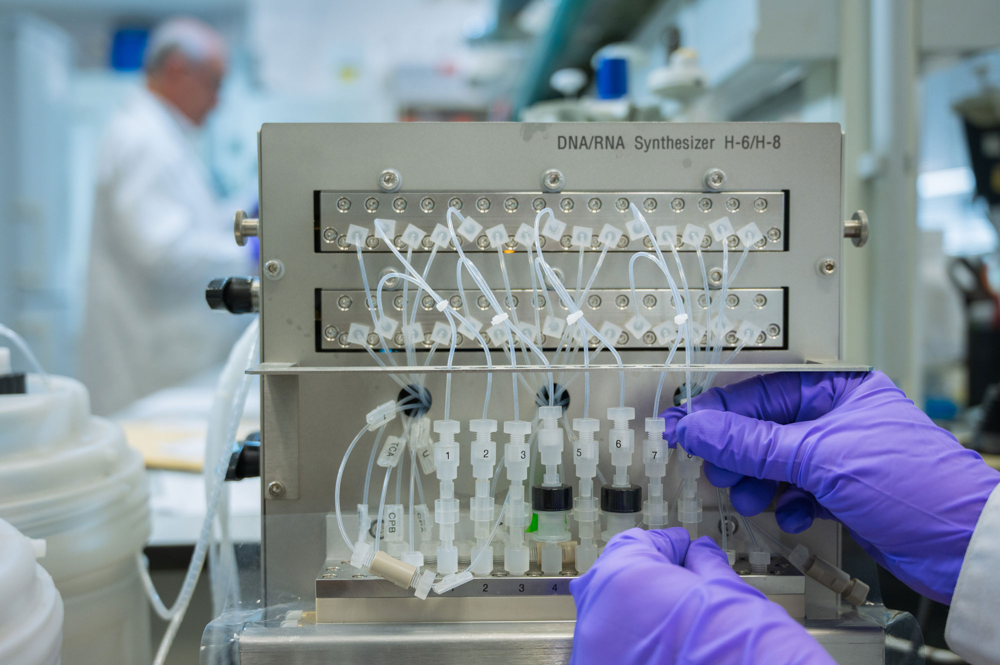 Investigadora manipula un sintetizador de ADN y ARN en un laboratorio de química de ácidos nucleicos.